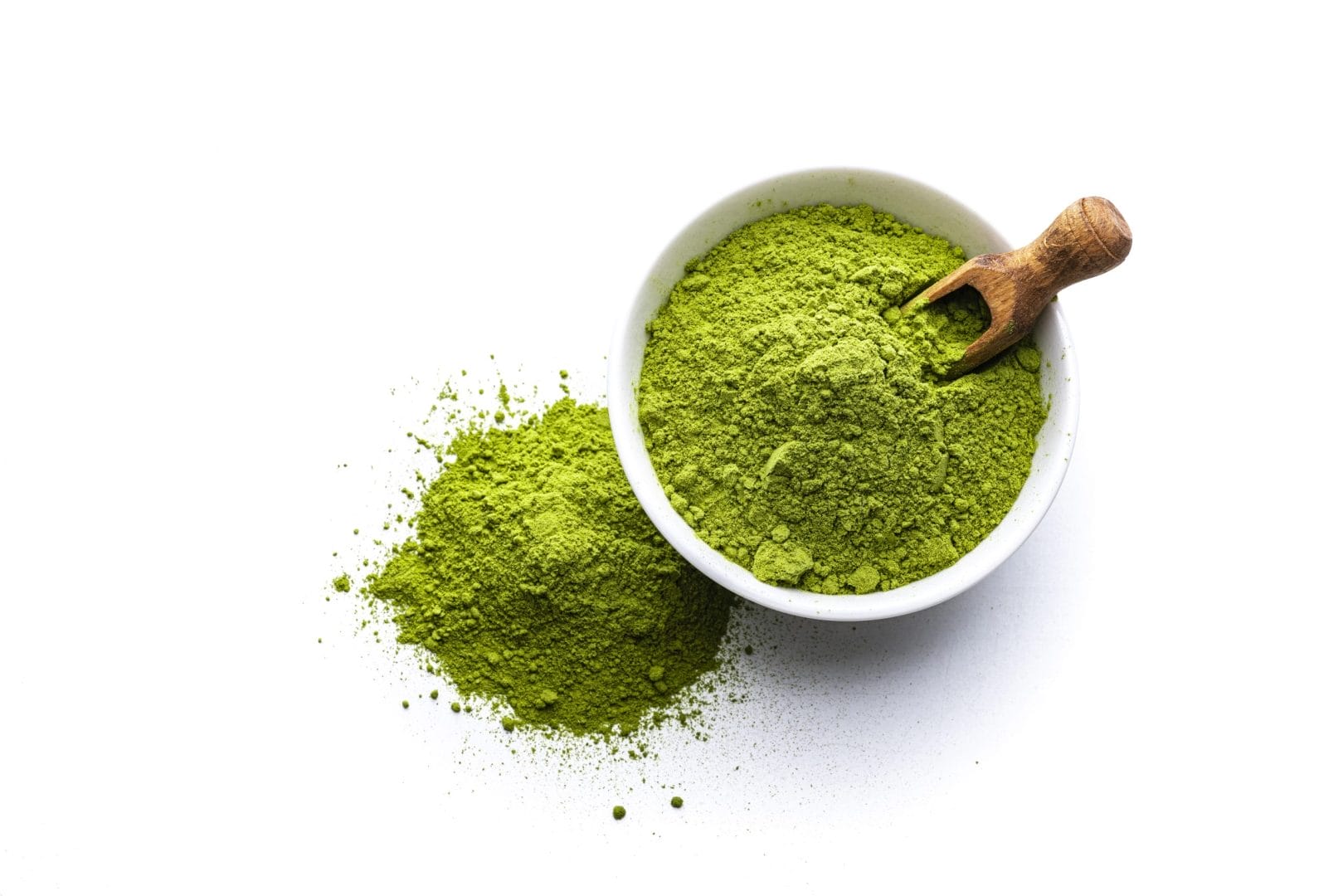 Matcha or green superfood powder in a white ceramic bowl with wooden spoon on white background.