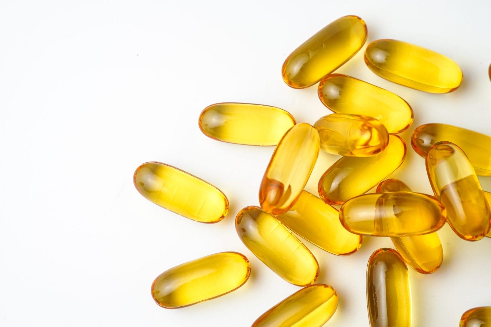 Golden softgel capsules on white background for dietary supplements or fish oil products.